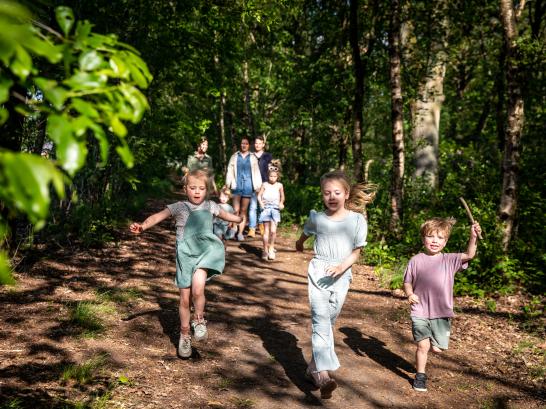 Kindjes rennen in een bos de moeders stappen erachter