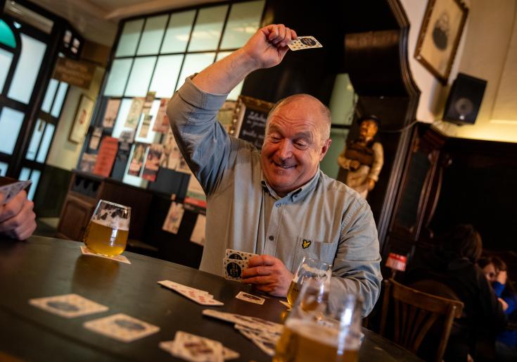 Man die een kaartspel speelt en een pintje drinkt op café