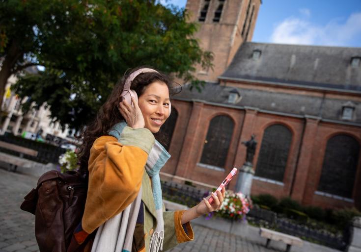 Vrouw die door Turnhout wandelt en een podcast luistert