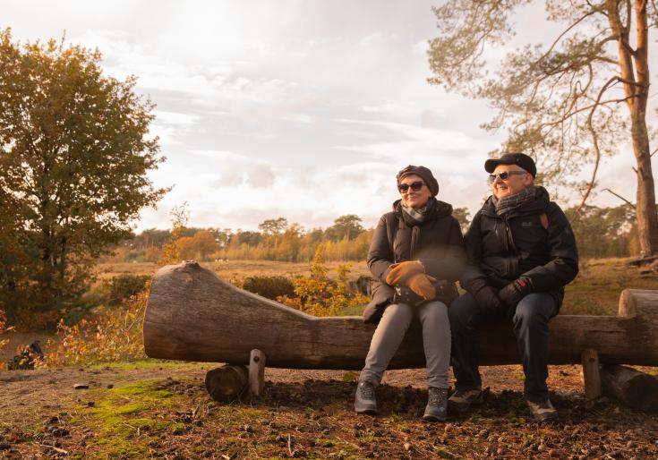 Man en vrouw zitten op een bankje in de natuur
