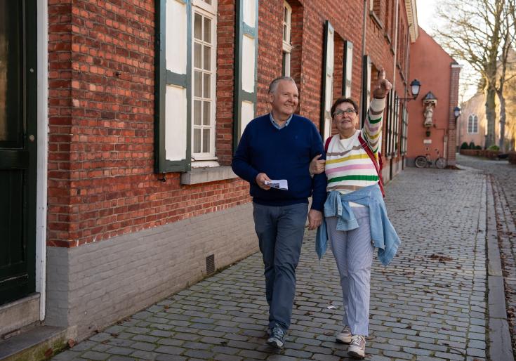 Man en vrouw die door het begijnhof wandelen en een zoektocht doen.