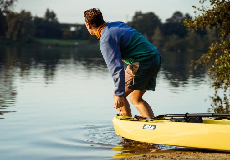 Man die kajak in het water trekt